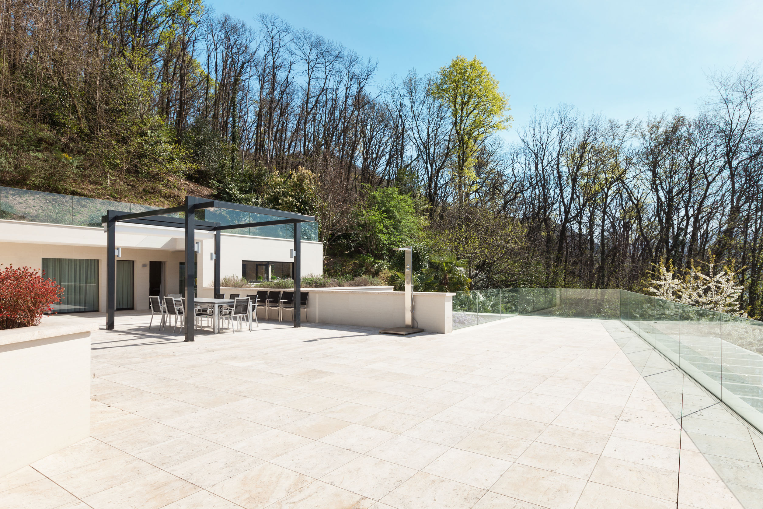 Terrasse mit Steinfliesen auf der mehrere Tische mit Stühlen stehen